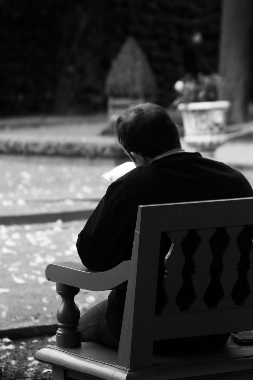 grayscale photo of man sitting on armchair